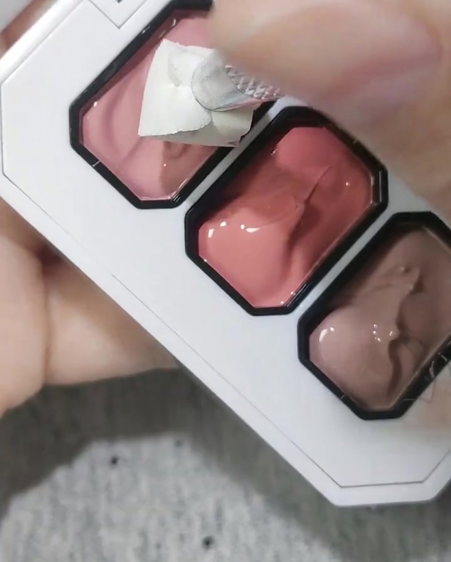 Una esponja cosmética utilizada para aplicar gel rosa sobre la punta de una uña.