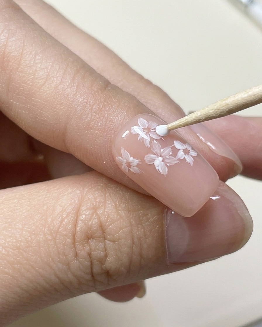 Pincel de detalle pintando una segunda capa de pétalos blancos escalonados sobre la primera.
