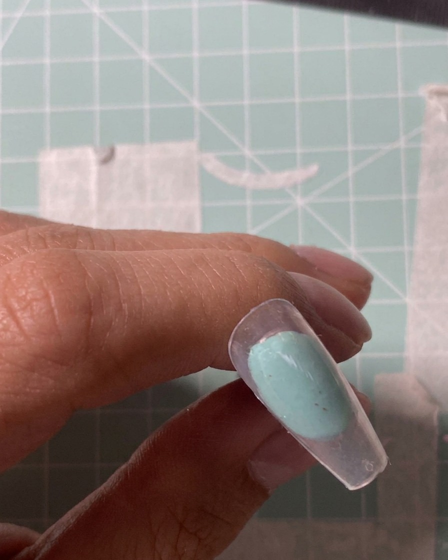 Primer plano de una punta de fresa eléctrica puliendo la superficie de un tip transparente.