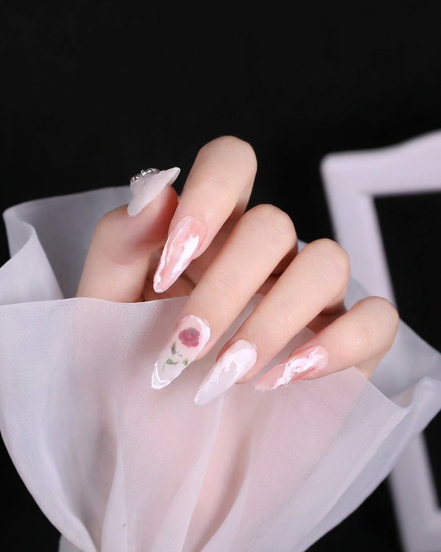 Un pincel de nail art aplicando un remolino de gel blanco espeso y texturizado en el área de la cutícula de una uña.
