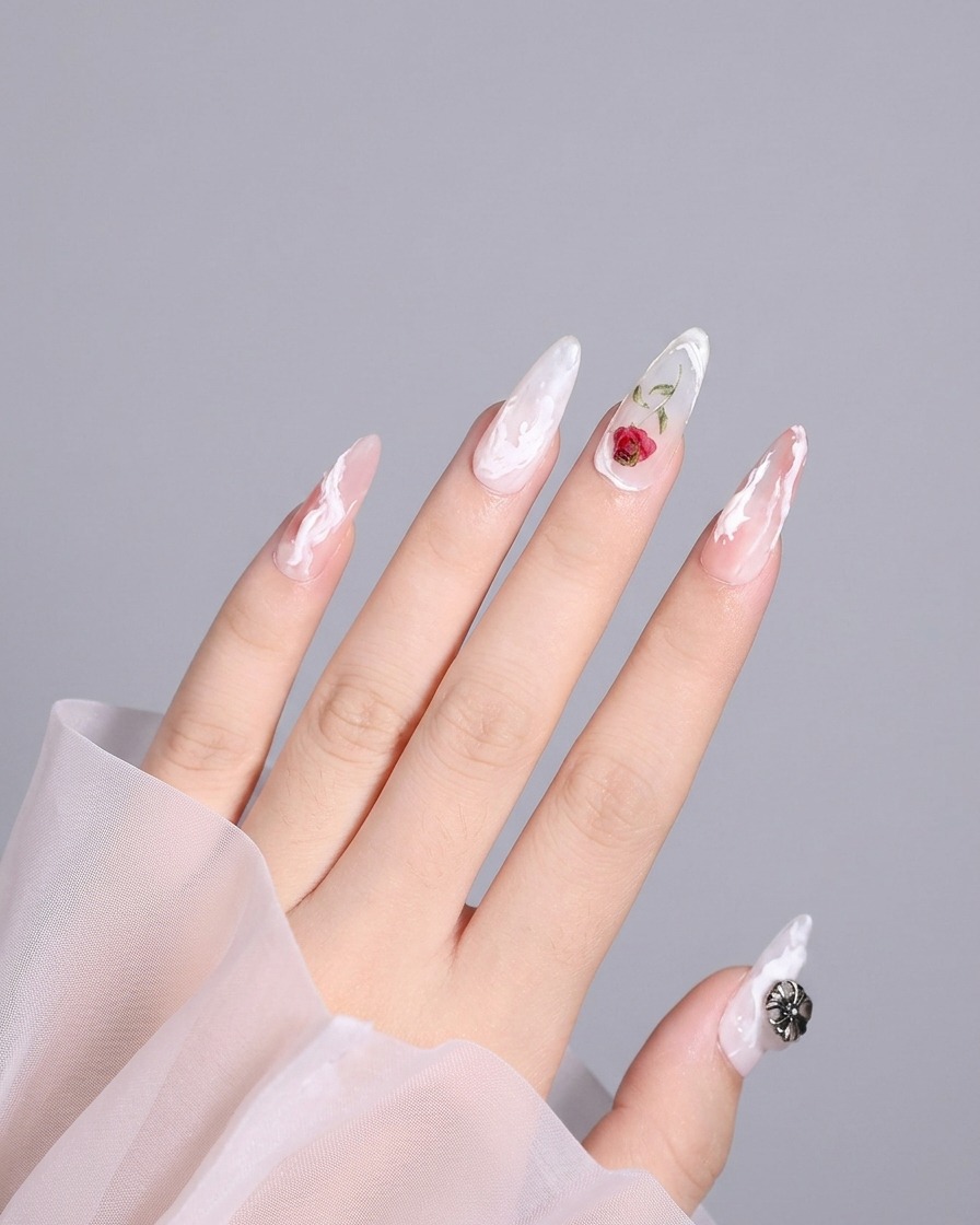 Toma detallada de una uña del pulgar con un diseño 3D completado que incluye un remolino blanco cerca del borde.