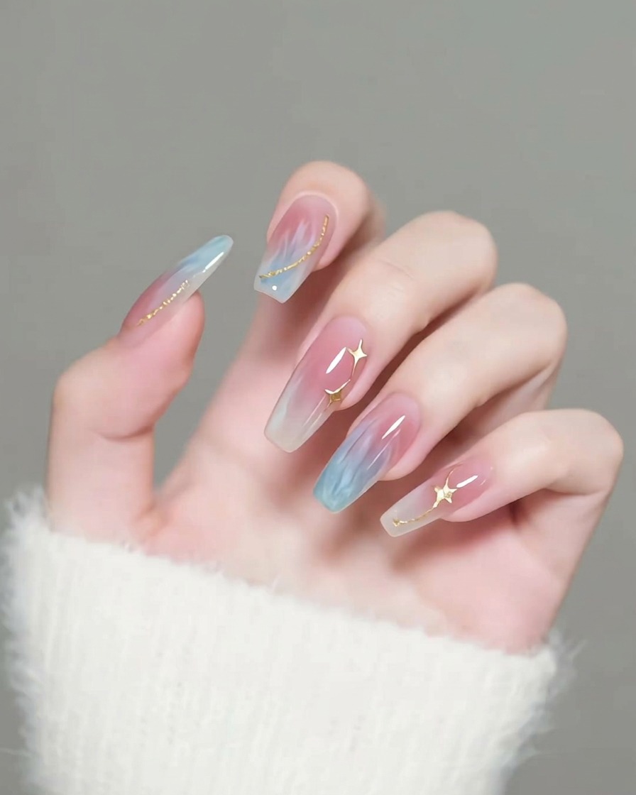 Pincel aplicando un top coat transparente y brillante sobre uñas decoradas con estrellas doradas.