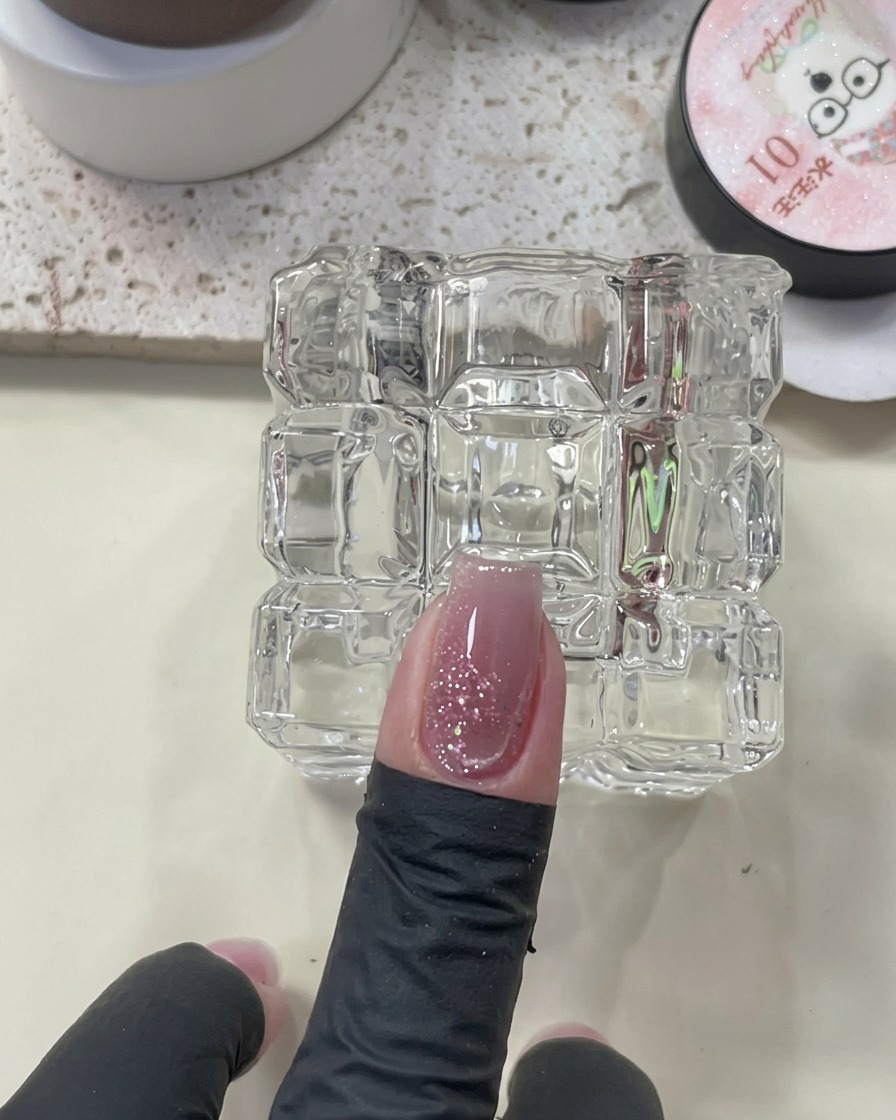 Un imán colocado sobre una uña húmeda con esmalte cat eye para crear el efecto brillante.