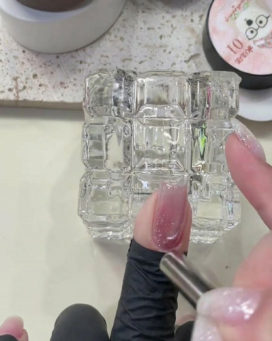 Primer plano de un imán dando forma al pigmento cat eye sobre la base de glitter.