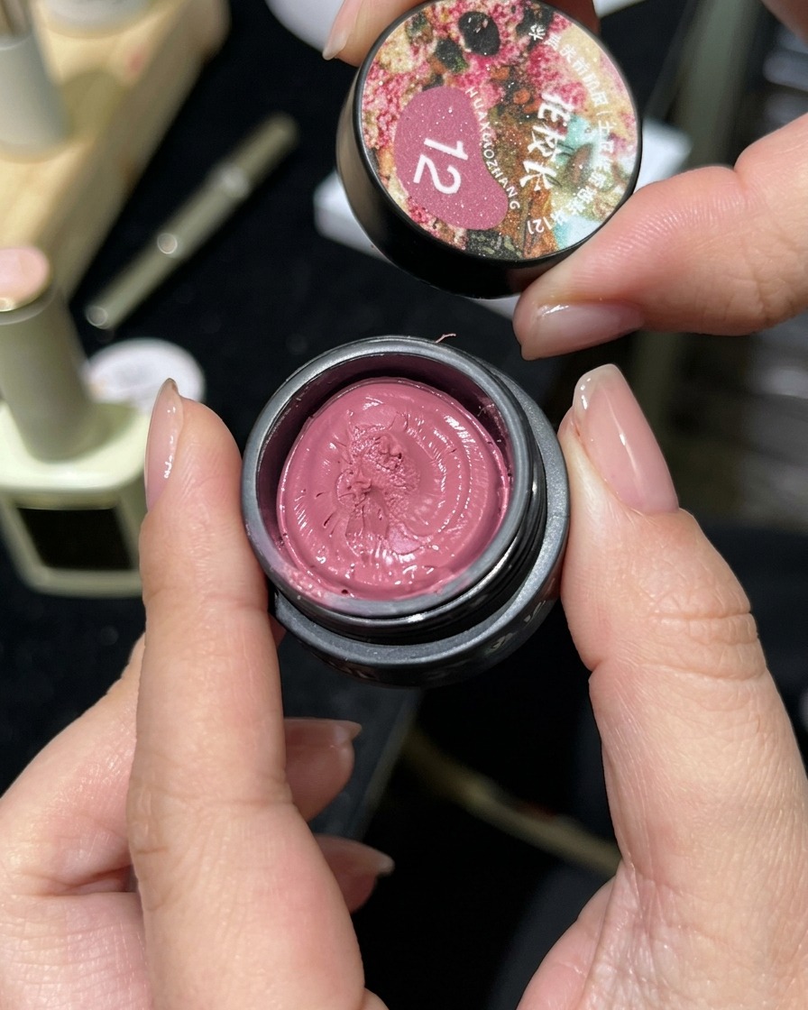 Un pequeño tarro de gel magnético rosa cat-eye abierto, mostrando su textura similar a una arcilla.