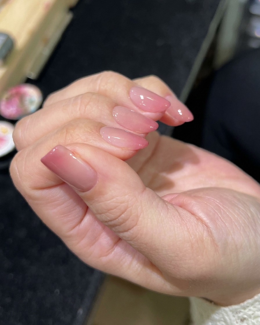 Un pincel aplicando un top coat transparente y brillante sobre el diseño de uñas magnético terminado.