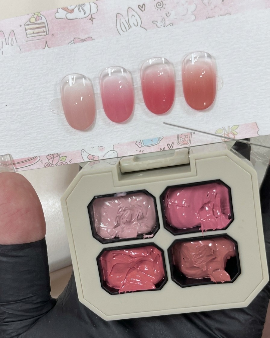 Una pequeña cantidad de gel rosa cremoso depositado sobre una superficie blanca junto a la paleta principal.