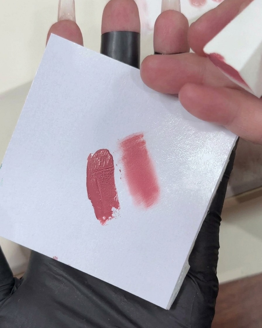 Una esponja de maquillaje con un degradado de gel rosa claro siendo aplicada en la punta de una uña.