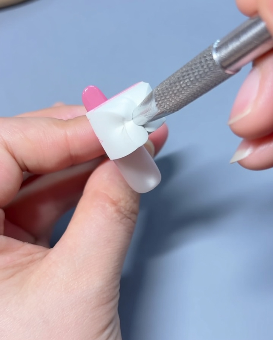 Aplicando una gota de esmalte de gel rosa en la punta de la uña preparada.