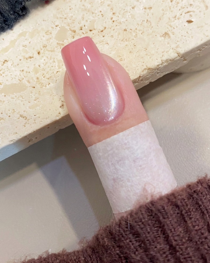 Herramienta magnética sostenida cerca del lateral de la uña, creando una línea de brillo diagonal en el gel húmedo.