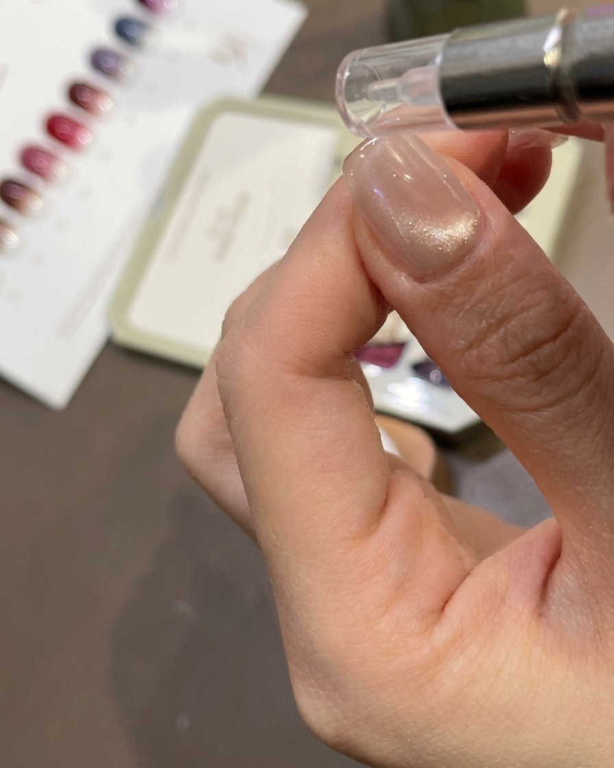 Un imán cilíndrico siendo sostenido cerca de una uña para atraer el brillo magnético hacia un efecto cat-eye.