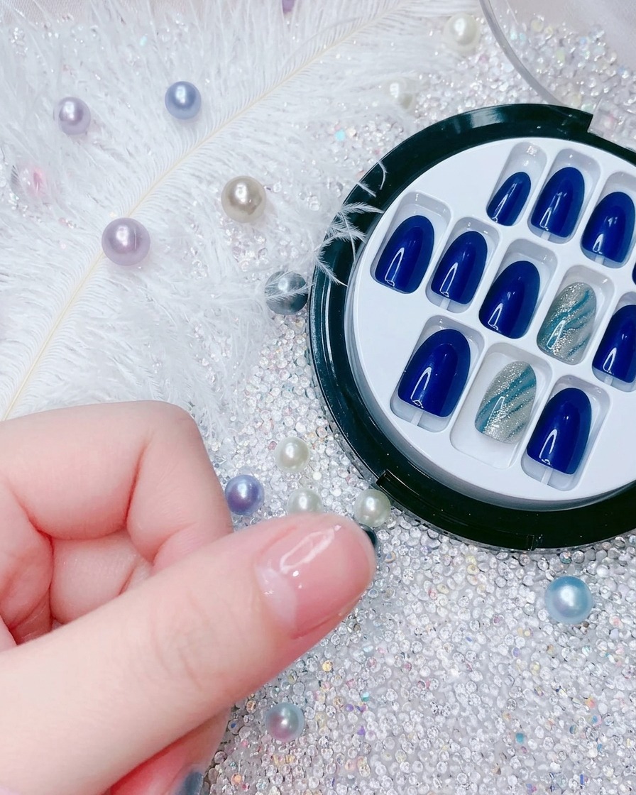 Primer plano que muestra una mano posicionando una nueva uña postiza azul eléctrico sobre el dedo índice.