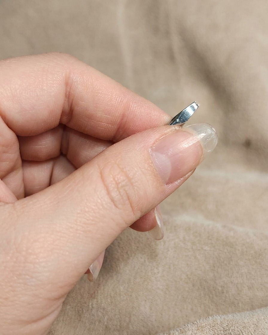 Primer plano de una uña siendo frotada con polvo cromo blanco usando un dedo.