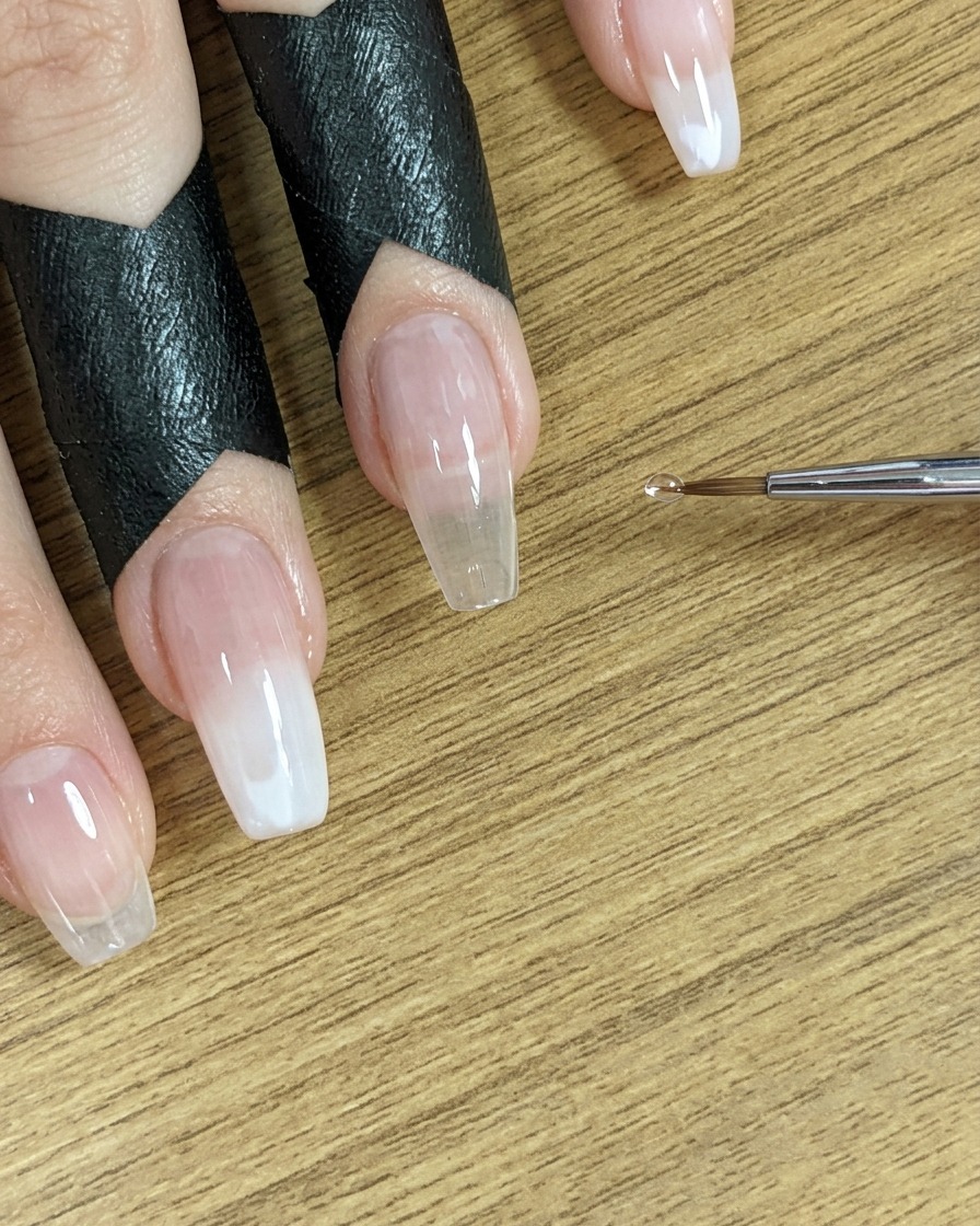 La punta de un pincel cerca de las uñas, lista para el siguiente paso.