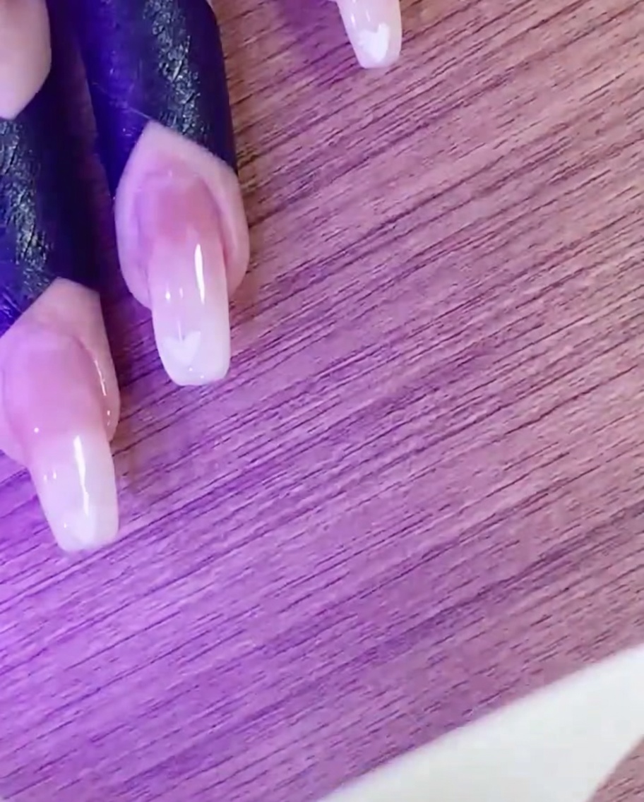 Una mano curando el diseño de corazón en la lámpara UV/LED.