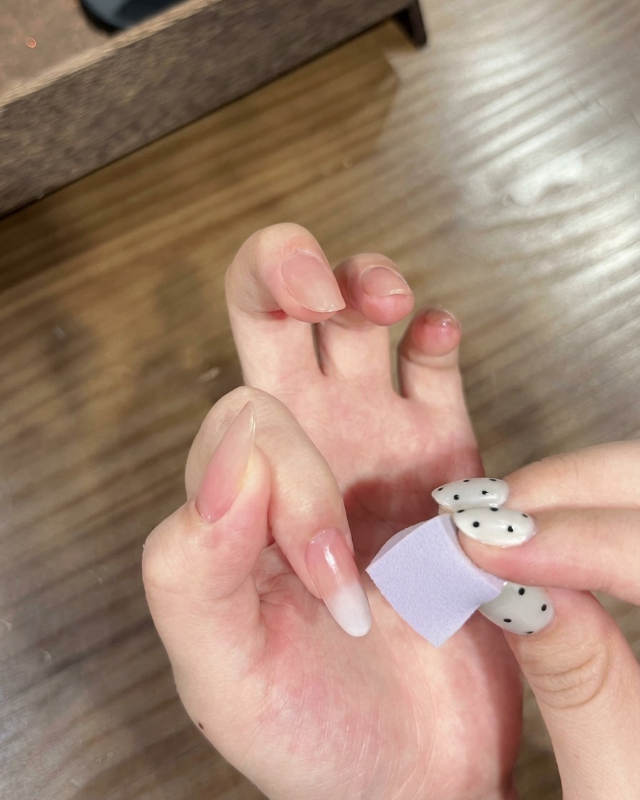 Una mano con uñas ombré siendo colocada bajo una lámpara UV/LED para curar el degradado.