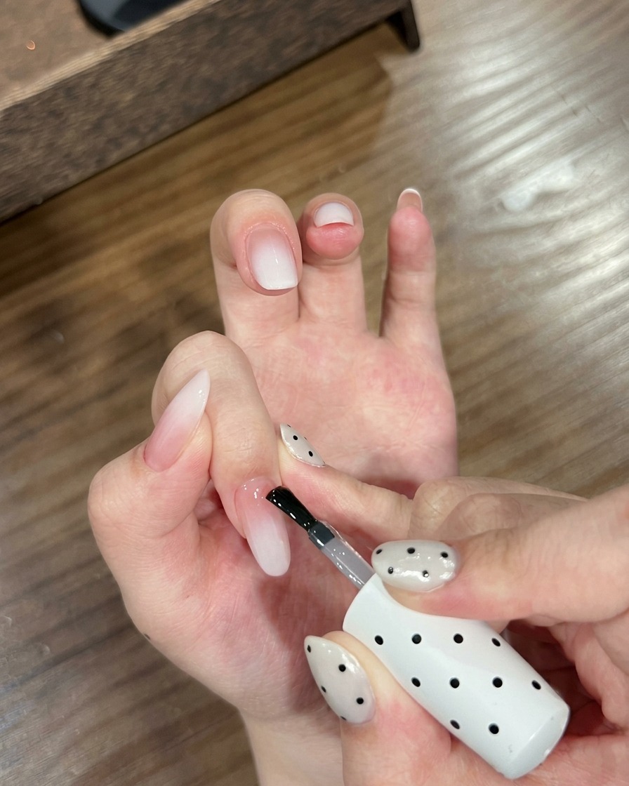 Primer plano de una mano con uñas degradadas posicionada dentro de una lámpara UV para uñas.