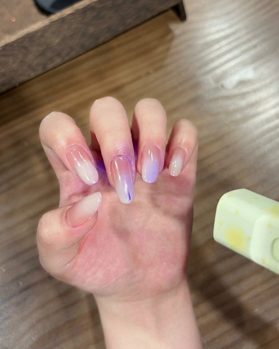 Una mano con uñas degradadas y cromadas colocada dentro de una lámpara UV/LED para curado.