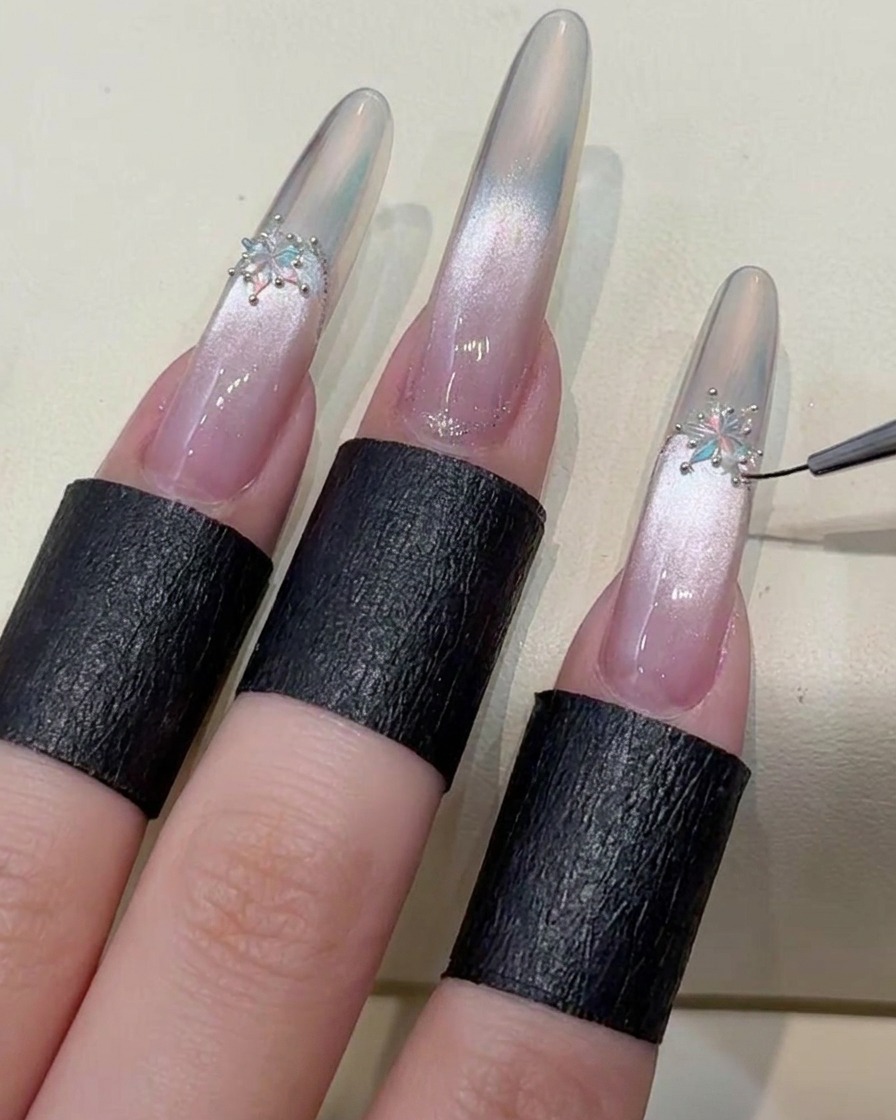 Un pincel aplicando un top coat final de estilo duro para sellar los bordes de la uña y los cristales decorativos.
