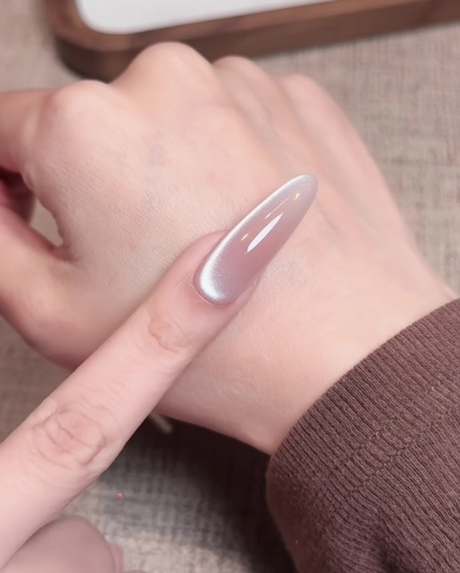 Una toallita sin pelusa siendo utilizada para limpiar la superficie de una uña de gel nude curada.
