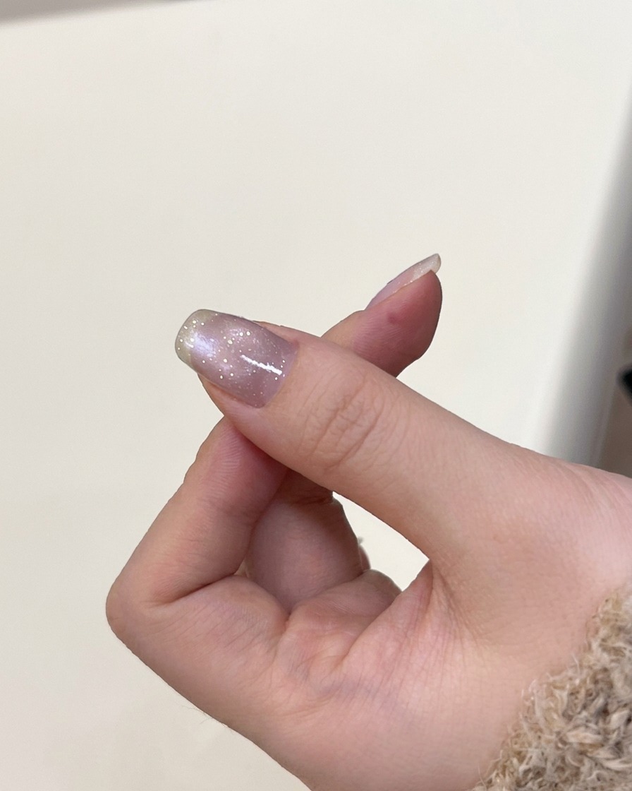 Una mano posicionada dentro de una lámpara de uñas UV para curar el gel aplicado recientemente.