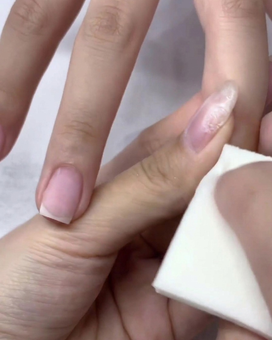 Primer plano de una mano dentro de una lámpara de uñas UV/LED durante el proceso de curado.