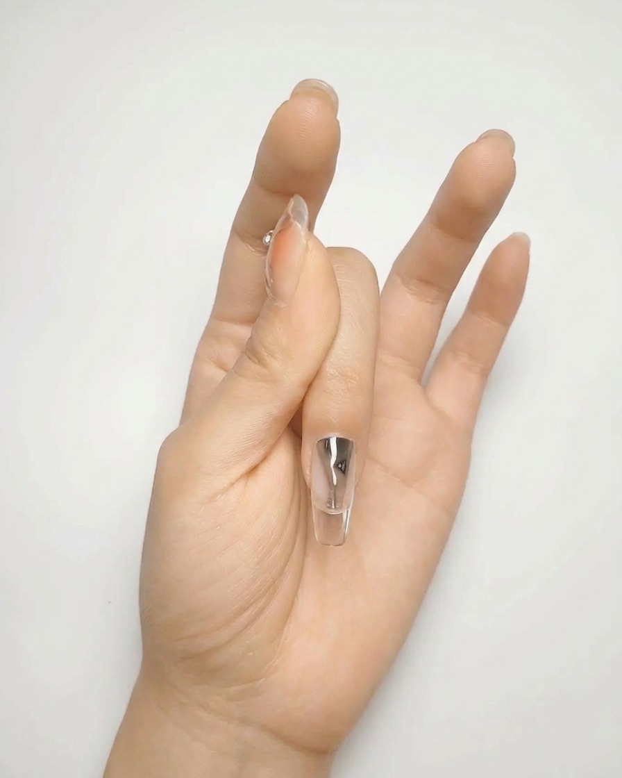 Primer plano de un pincel aplicando una segunda capa de esmalte de gel nude para lograr una superficie uniforme y opaca.