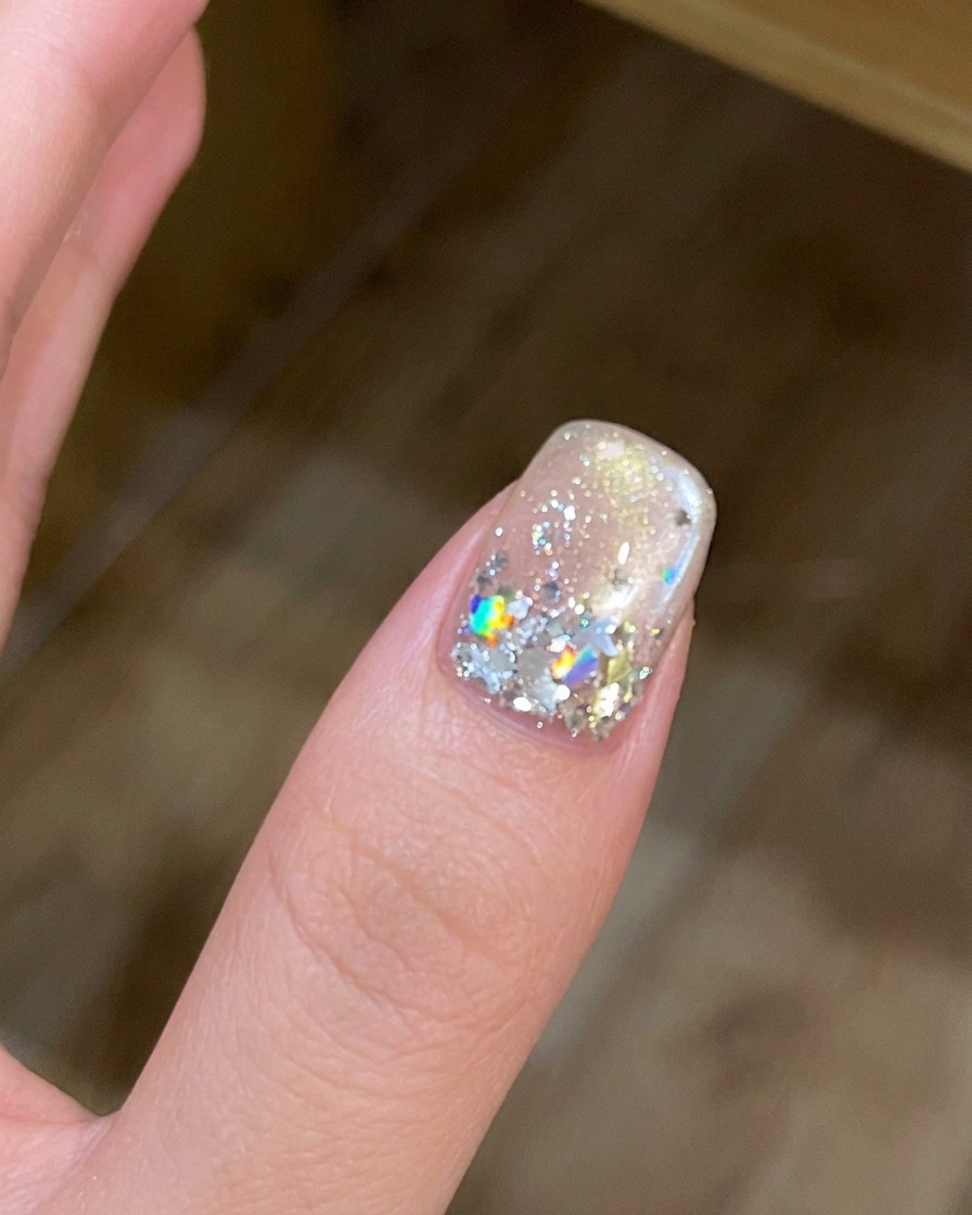 Una mano dentro de una lámpara de uñas UV/LED con la luz encendida.