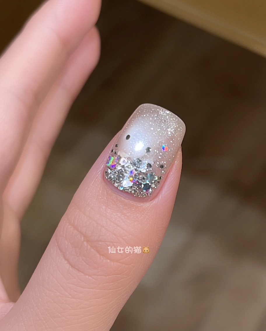 Un pincel aplicando una capa final de top coat brillante y transparente sobre una uña decorada con estrellas.