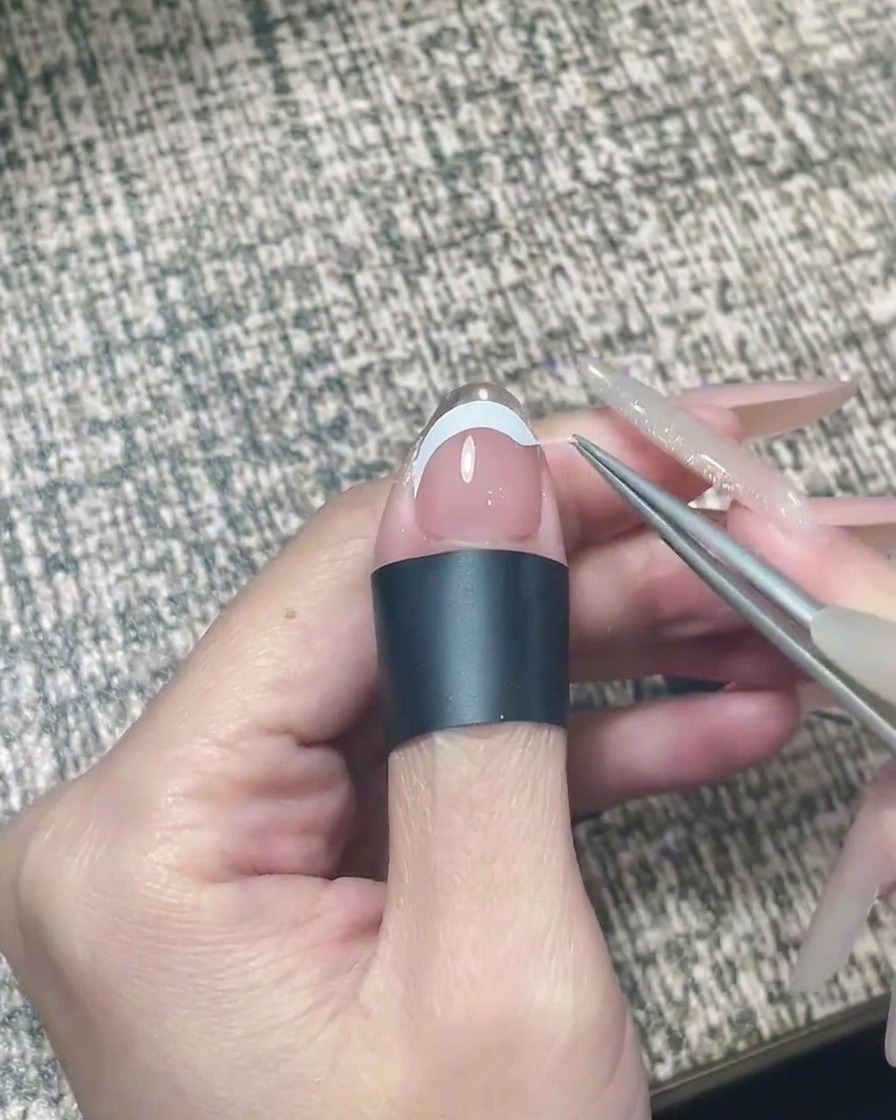 Una lima de uñas puliendo suavemente el borde libre de una uña con cromo plateado aplicado.