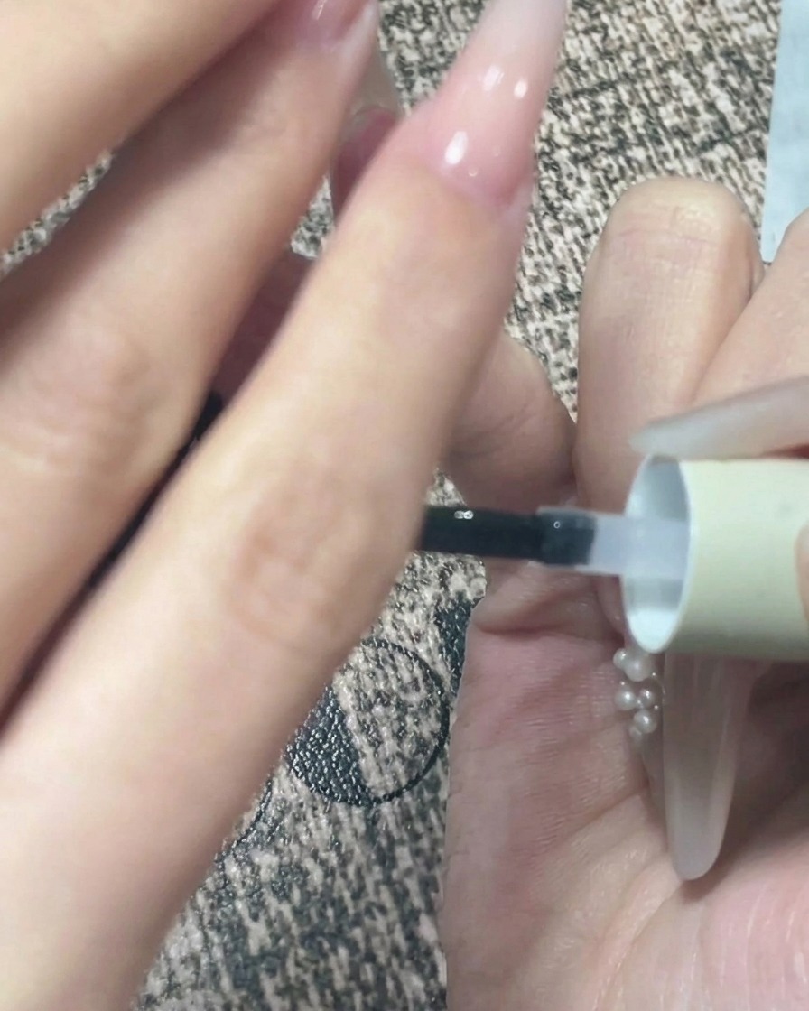 Primer plano de una mano boca abajo después de la aplicación del top coat para permitir que el gel se nivele por sí solo.