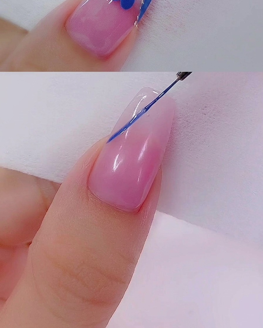 Un pincel aplicando una segunda capa de esmalte de gel azul en la punta francesa para una cobertura uniforme.