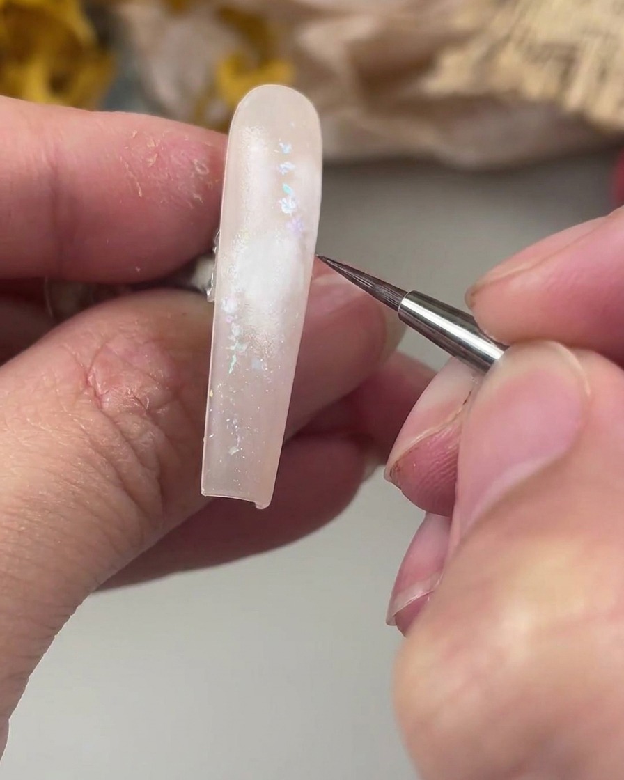Un pincel liner fino sobre el área pintada de blanco, listo para pintar el centro delicado de la rosa de acuarela.