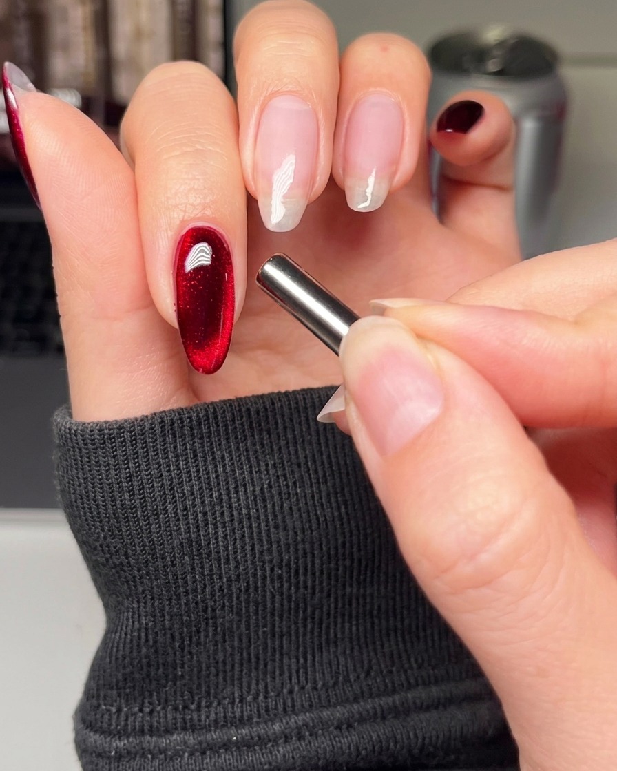 Un pincel de uñas aplicando una capa suave de esmalte en gel negro sobre la uña del dedo índice.