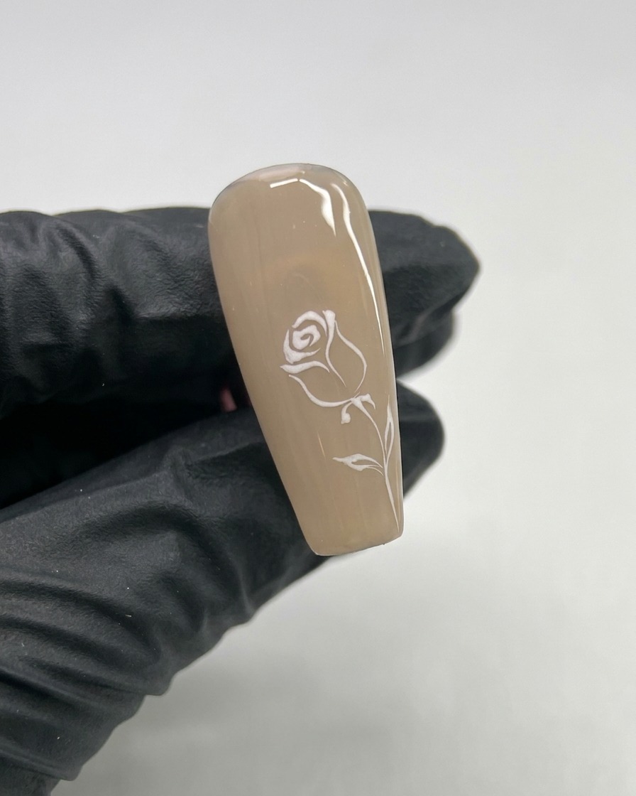 Primer plano de una uña con un pequeño corazón de gel blanco pintado en el centro.
