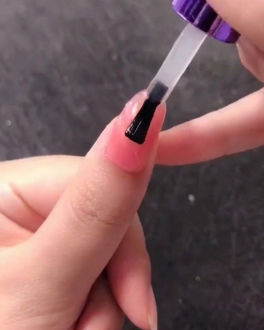 Un pincel aplicando una capa de gel transparente sobre el diseño texturizado de concha.