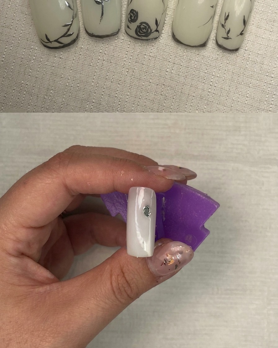 Una uña mostrando los trazos iniciales de plata metálica formando la base de un diseño floral.