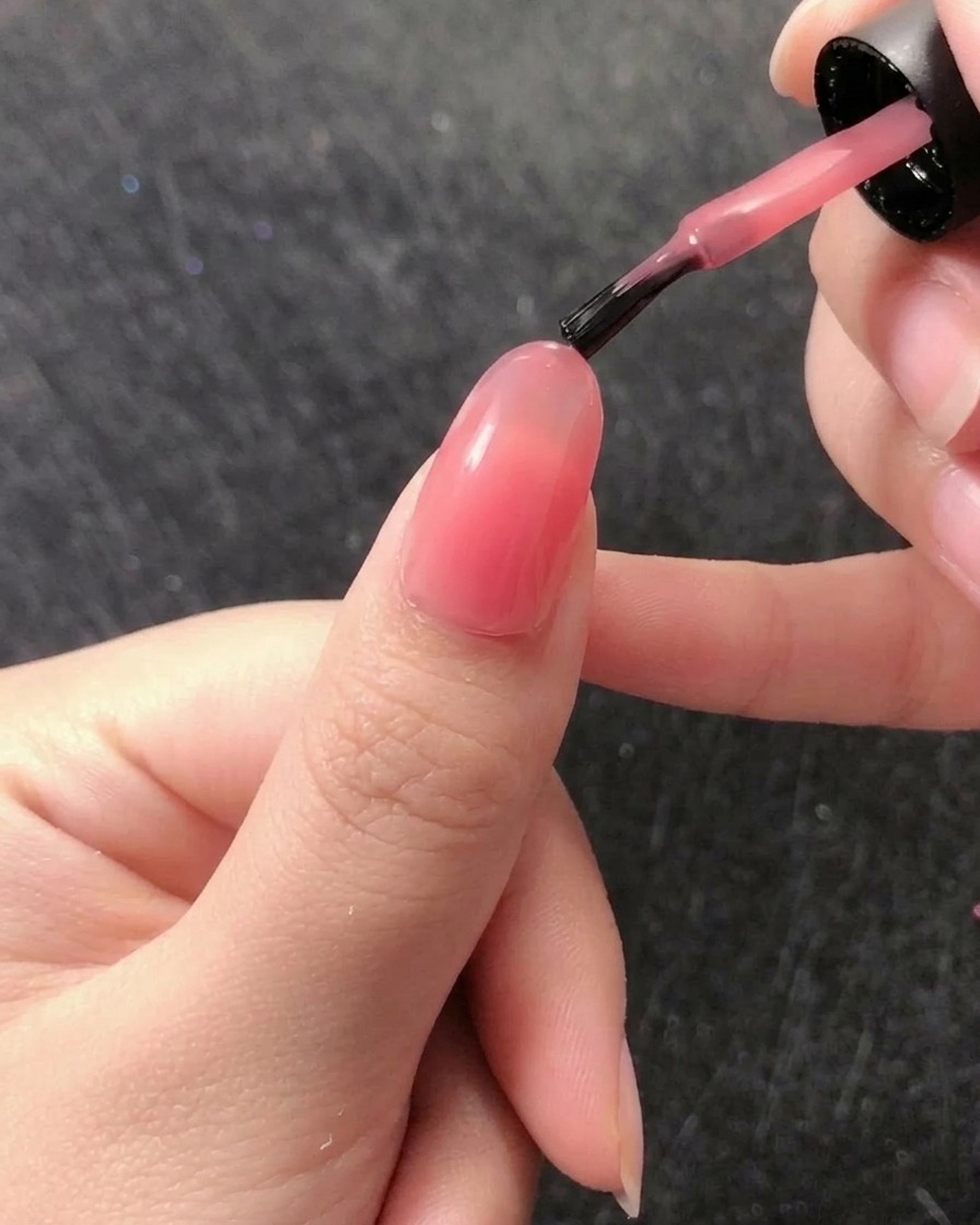 Pincel fino tipo liner recogiendo una pequeña gota de gel constructor transparente del envase.