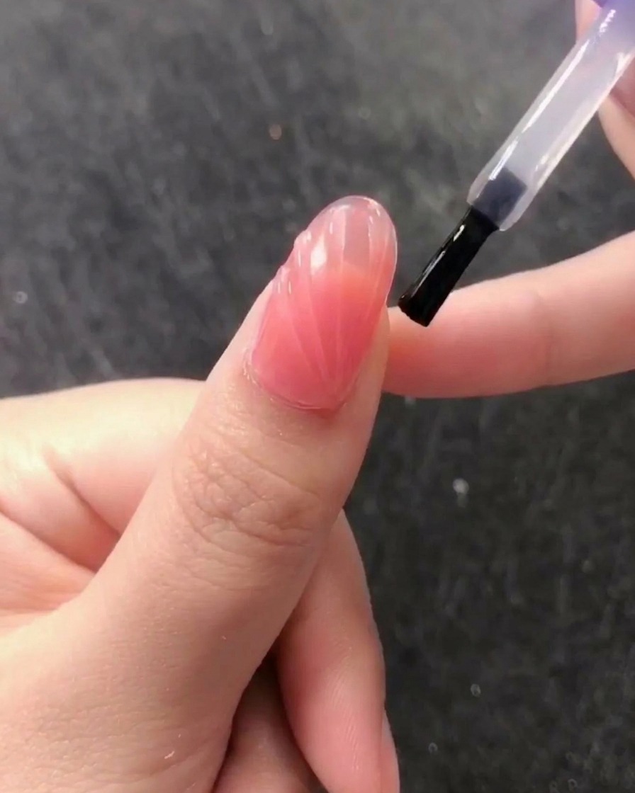 Pincel aplicando un top coat brillante sin capa de inhibición sobre el diseño texturizado.