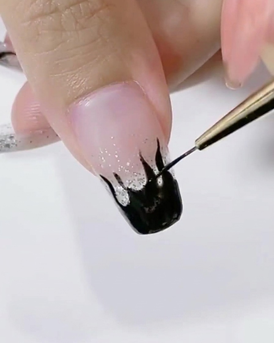 Detalle de un pincel liner suavizando el borde de un diseño de llama negra.