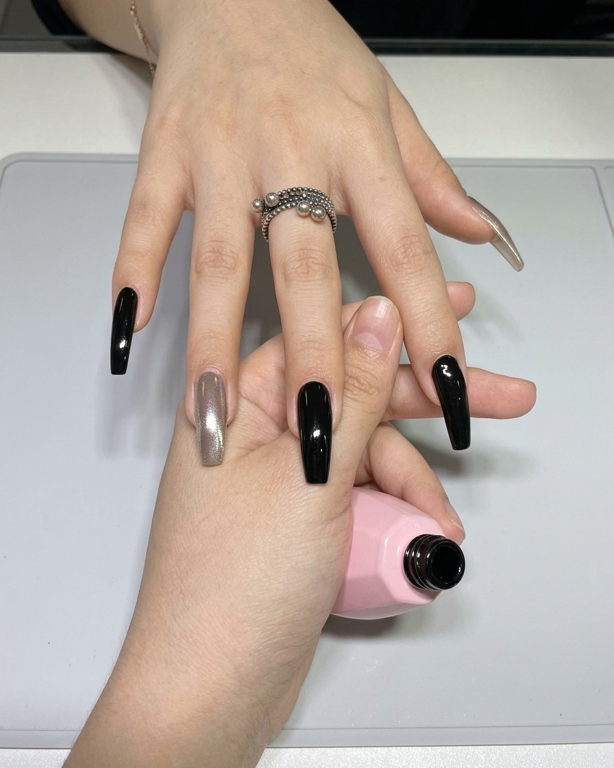 Primer plano de un pincel fino para nail art (liner) siendo cargado con esmalte de gel negro desde una pequeña paleta.