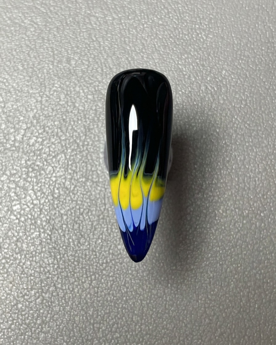 Una franja horizontal de esmalte en gel azul aplicada en la punta de la uña pintada de negro.