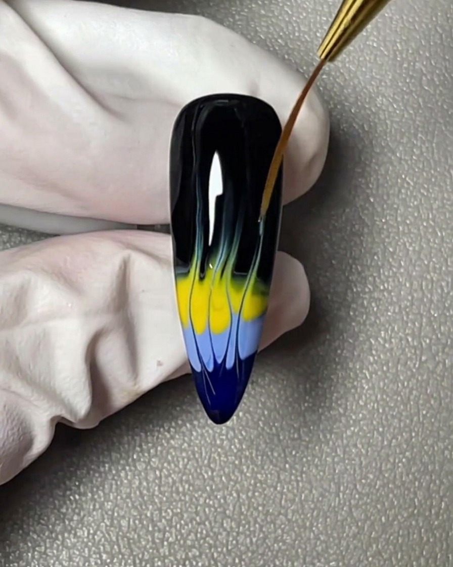 Una franja horizontal de esmalte en gel amarillo aplicada justo encima de la banda azul en la punta de la uña.