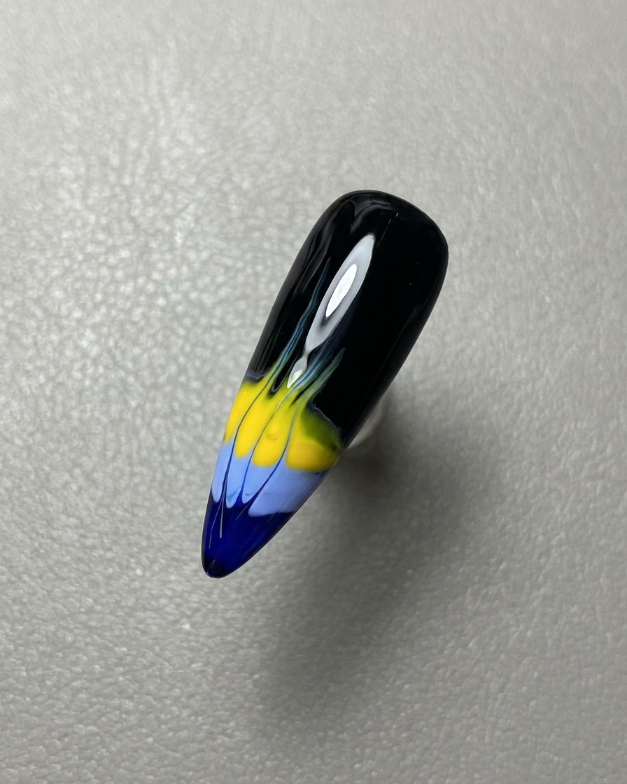 Un pincel aplicando una capa de top coat de gel transparente y brillante sobre el diseño de llamas terminado.