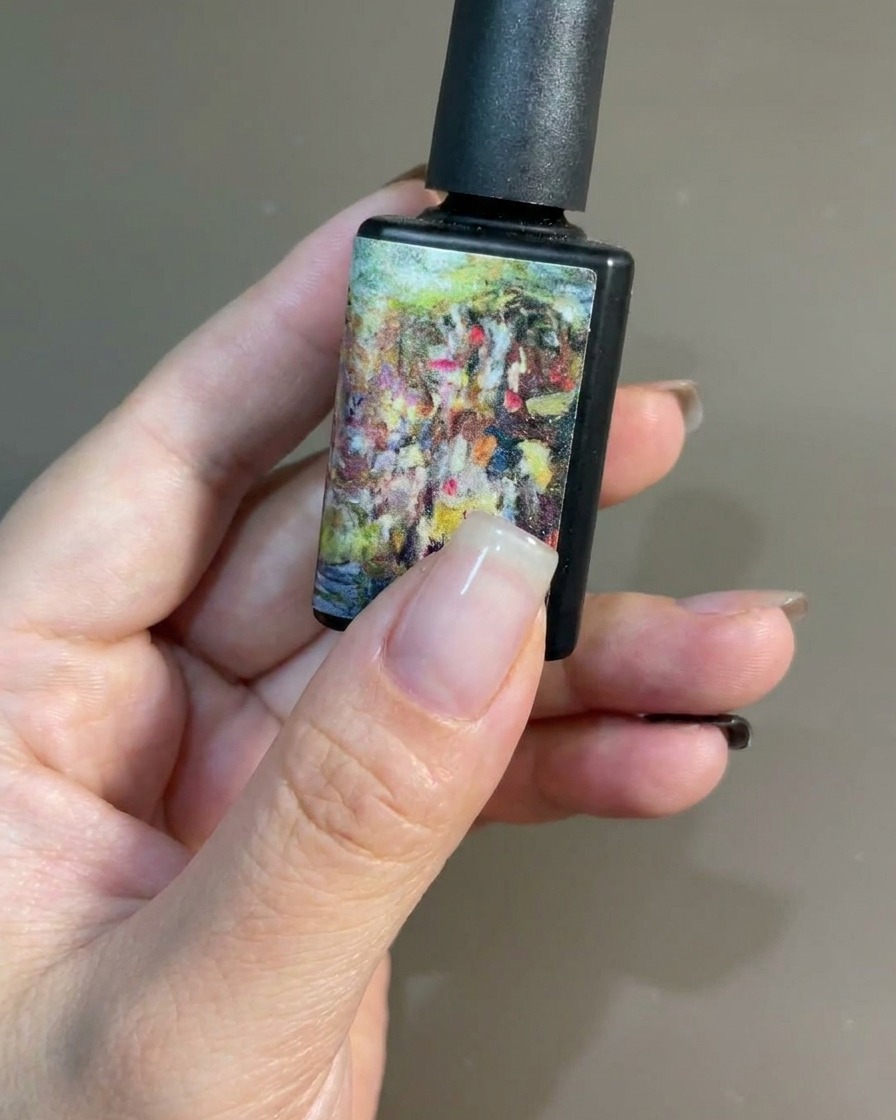 Un pincel aplicando una capa suave de esmalte de gel negro sobre una uña natural.