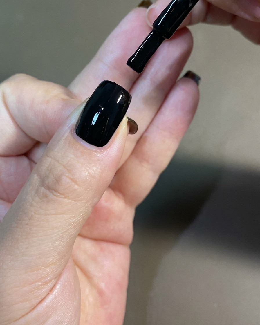 Una mano colocada dentro de una lámpara de uñas UV profesional para el curado.