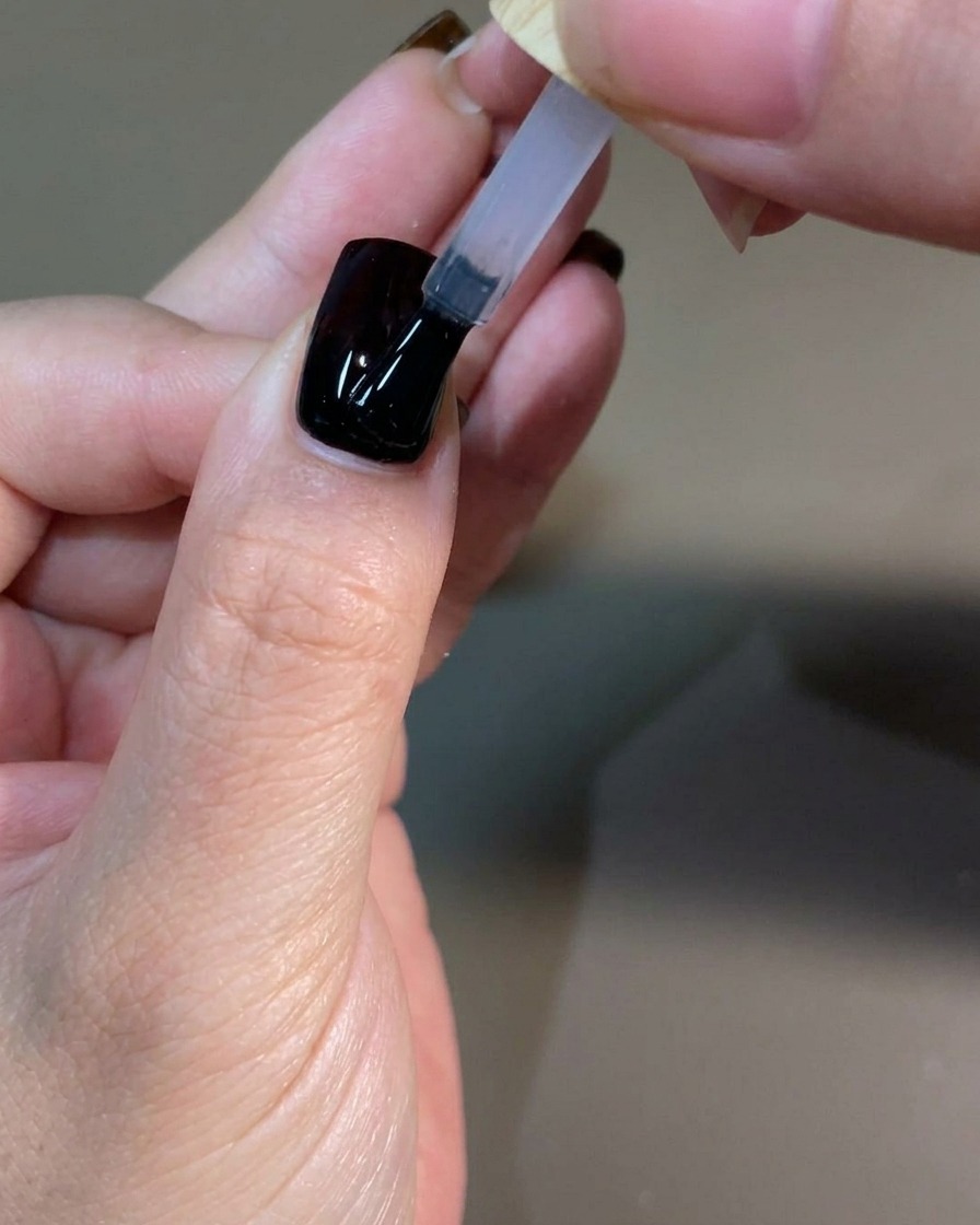 Una mano manicurada curando la capa final de top coat dentro de una lámpara de uñas UV profesional.