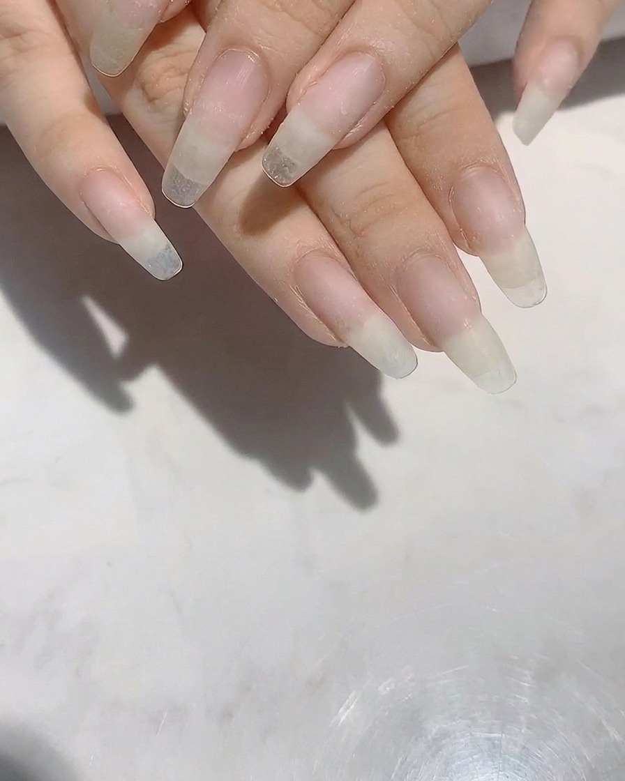 Manos con uñas naturales largas y con forma siendo refinadas con una lima de uñas.
