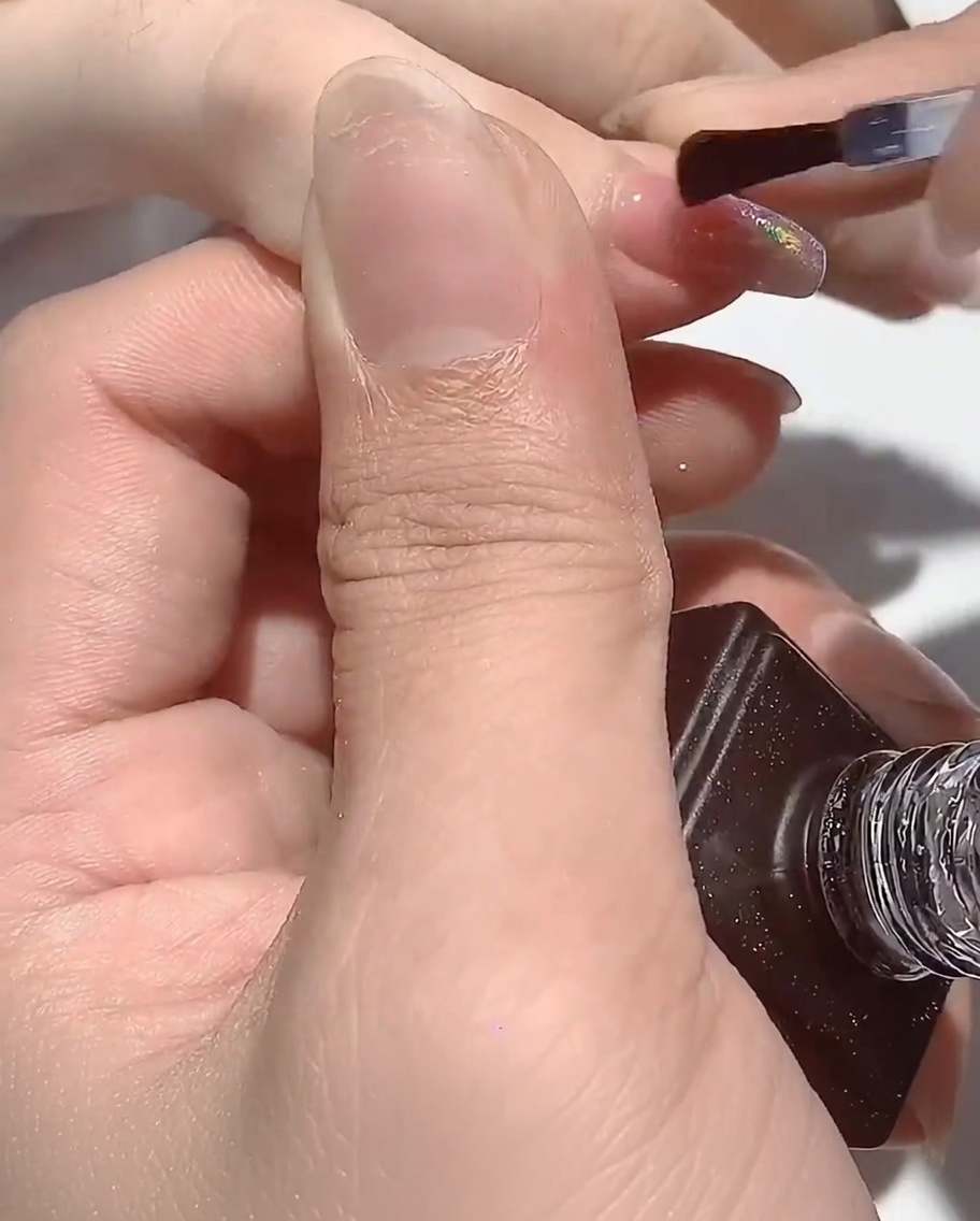 La mano descansando bajo la lámpara UV, con las uñas curándose.
