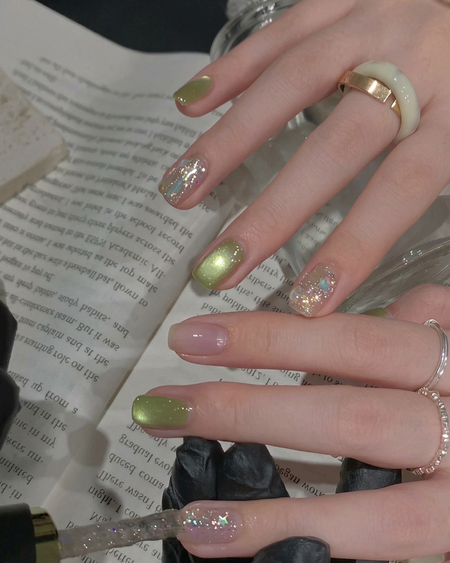 Un pincel aplicando esmalte de glitter plateado denso sobre una uña de acento.